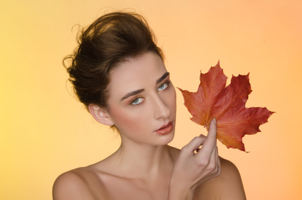 黄色背景上有秋叶的女人图片下载