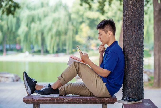 帅哥坐在长凳上享受他的智能手机图片下载