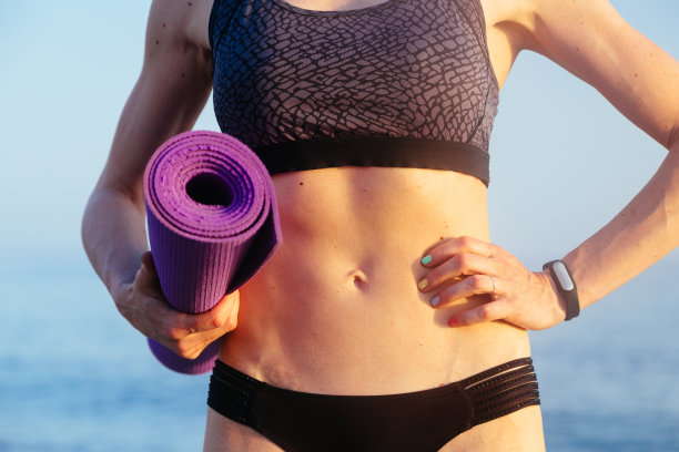 女人用完美的身体抱瑜伽垫。健康生活理念。图片下载