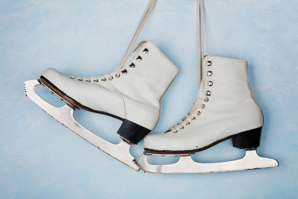 蓝色的墙上挂着花样滑冰用的老式冰鞋。素材图片