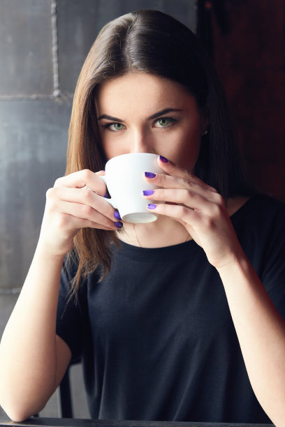 拿着杯子在咖啡馆喝茶的年轻女孩图片下载