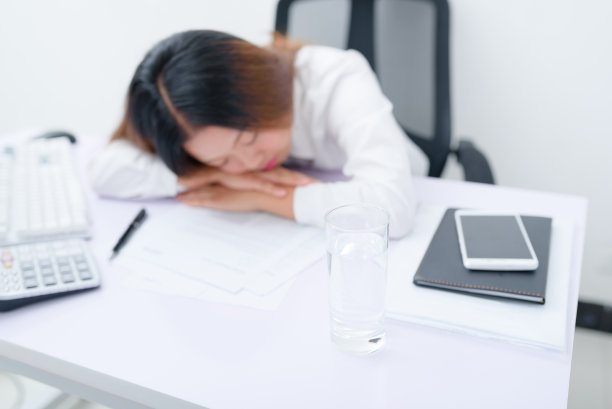 疲惫的女商人睡在办公桌上。图片下载