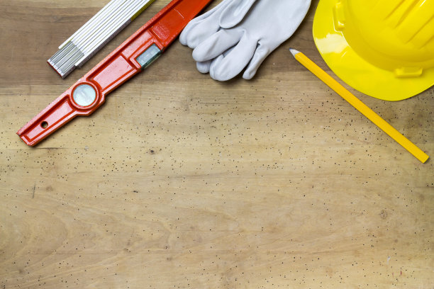 防护头盔，泥工工具和工程图纸上的木材背景图片下载