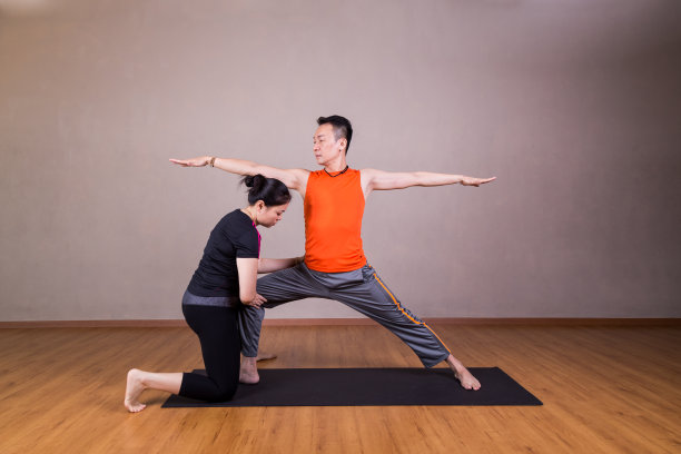 瑜伽教练纠正学生表演武士2或Virabhadrasana 2图片下载