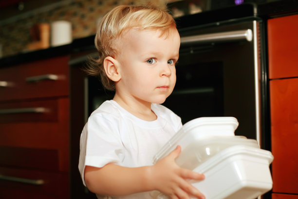 小男孩在厨房里拿着塑料容器图片下载