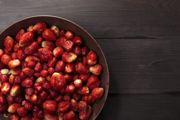 新鲜的草莓放进质朴的铜碗里图片下载