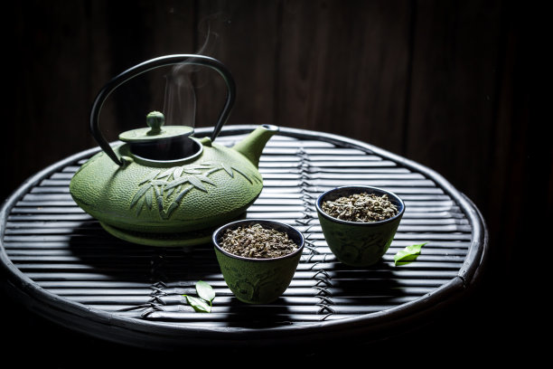 新鲜的绿茶和茶壶在黑色的桌子上图片下载