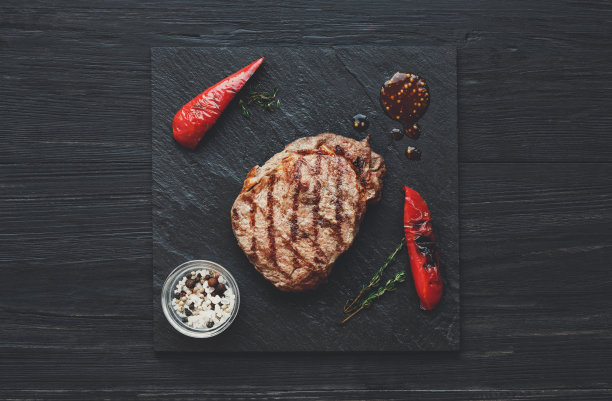 烤牛排在深色木制桌子的背景，俯视图图片下载