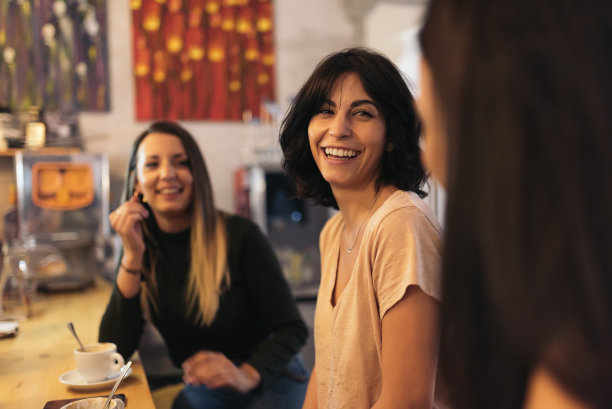 三个美女一边喝咖啡一边聊天。图片下载