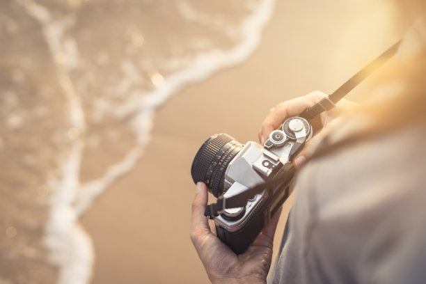 年轻的旅行者带着复古相机在海滩上图片下载