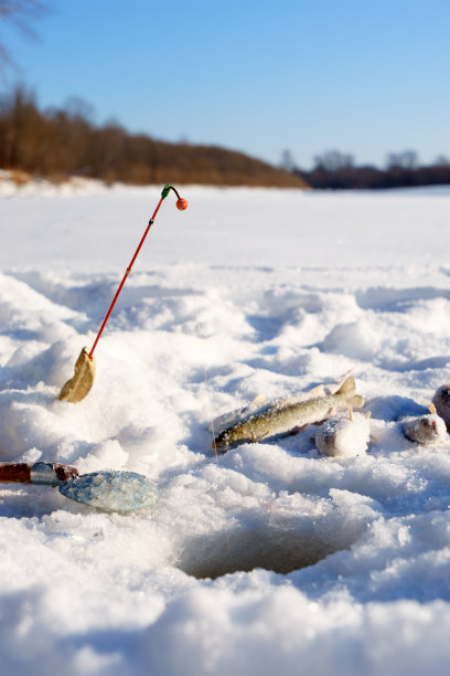 在靠近洞的冰上钓鱼和钓鱼图片下载