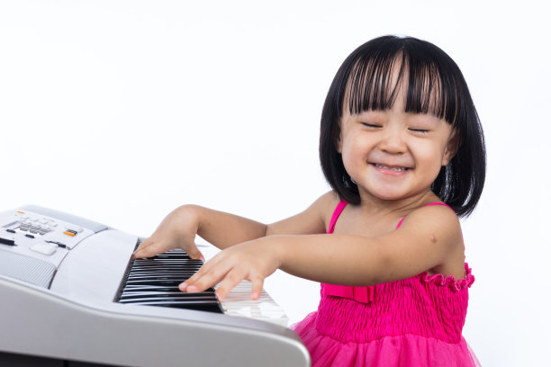 快乐的亚洲华人小女孩弹奏电子钢琴键盘图片下载