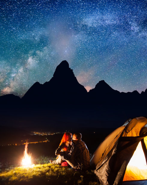 一对情侣在星光下的篝火和帐篷附近接吻图片下载