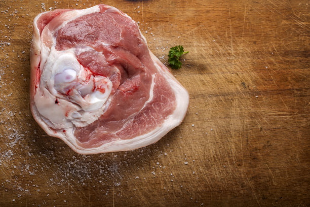一块加盐和欧芹的生猪肉放在木头上图片下载