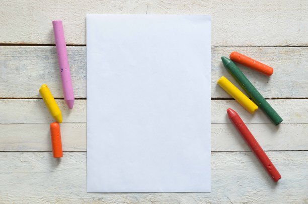 纸和一些蜡笔在教室的一张木桌上。图片下载