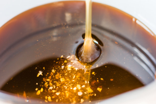 新鲜的，刚刚收集的蜂蜜正在倒入容器中图片下载