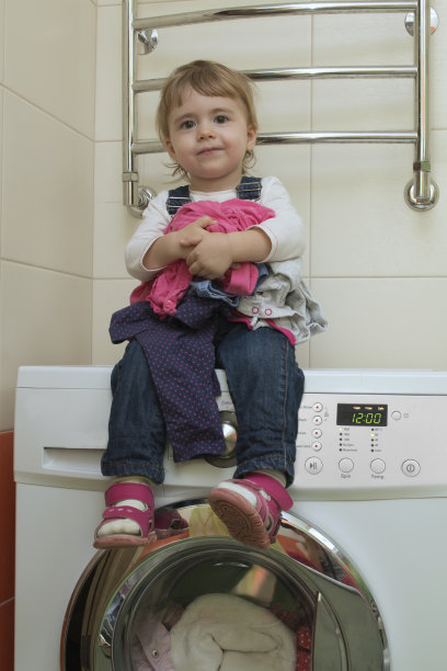 快乐可爱的小女孩坐在洗衣服上图片下载