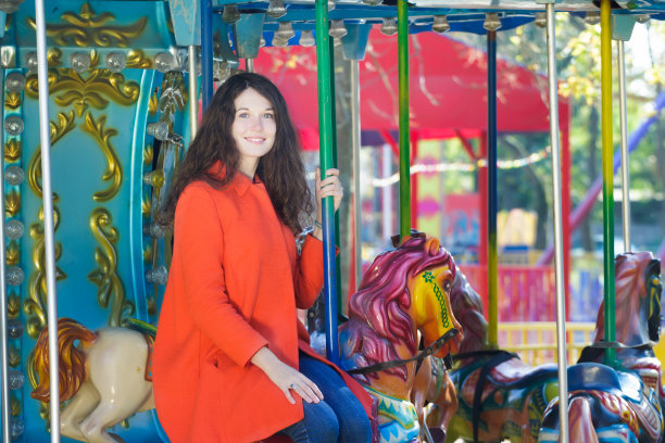 美丽的女人穿着橘色外套，骑马在户外旋转肖像图片下载