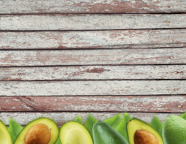 新鲜牛油果和树叶在木制背景。图片下载