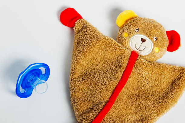 婴儿奶嘴和玩具躺在白色的背景上。图片下载