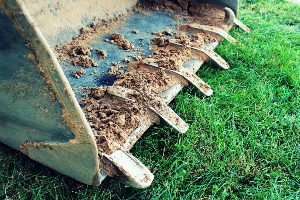 挖掘机斗在施工现场的草地上图片下载