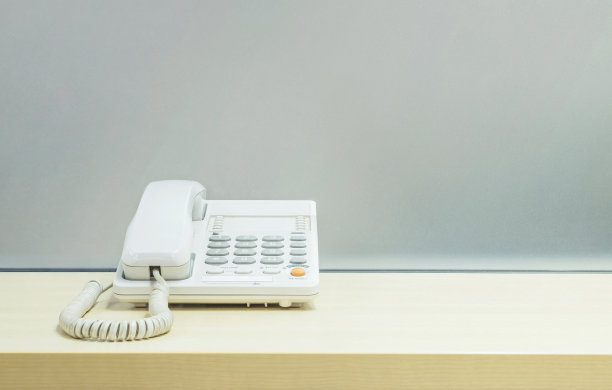 特写白色电话，木质办公桌上的办公室电话图片下载