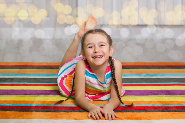 快乐的孩子躺在彩色地毯的背景上图片下载