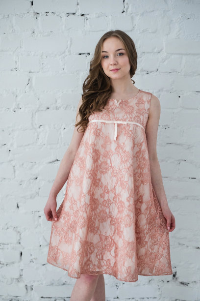 一个穿着桃红色裙子的女人靠在白色的砖墙上图片下载