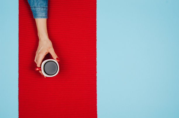 女人双手捧着咖啡放在五颜六色的桌子上，俯视图图片下载