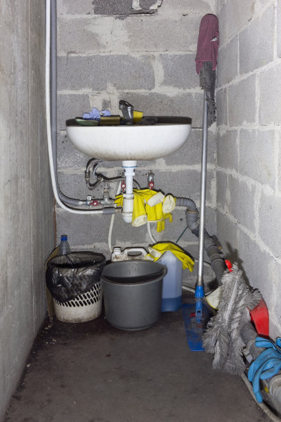 住着老鼠的地窖是一个概念。一个肮脏的洗涤盆，一个扫地机和一个装垃圾的桶，橡胶手套。用强光来强调情绪。图片下载