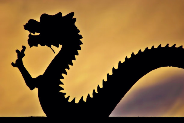 日落背景上中国龙的黑色剪影。图片下载