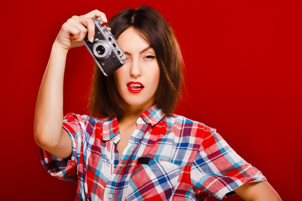 热情的女孩摆着红色背景的复古相机图片下载