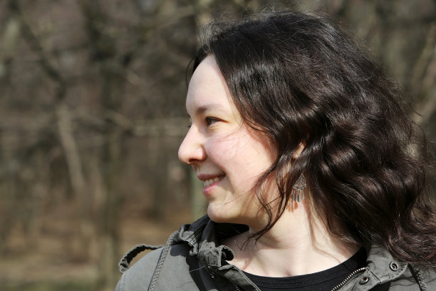 美丽的黑发微笑女孩和春天的绿色散景的背景图片下载