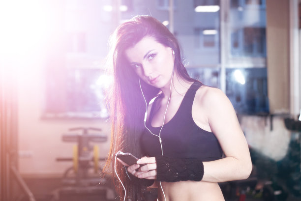 性感的健身女人在运动服装休息后哑铃锻炼在健身房。美丽的女孩聊天电话和放松训练后在健身房。图片下载