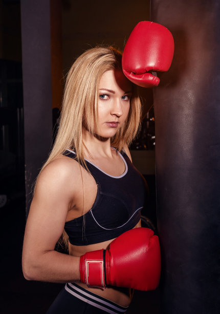 小女孩在体育馆做拳击训练。女拳击手粉碎沙袋。图片下载