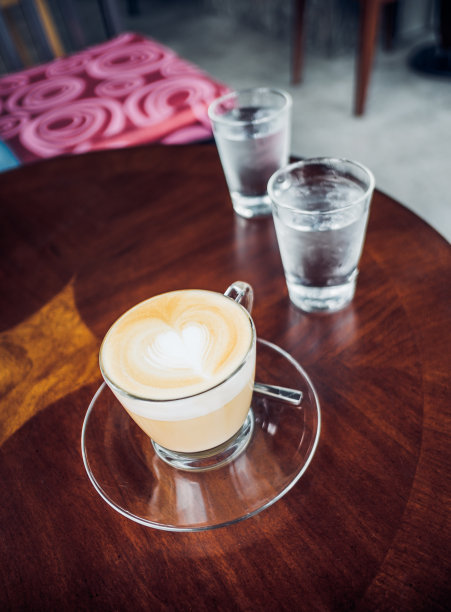 拿铁咖啡在咖啡吧的棕色木头桌面上的透明杯图片下载