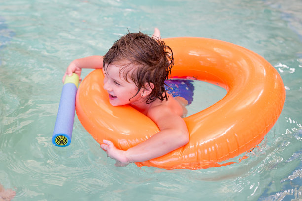 小男孩拿着水枪在游泳池里玩。图片下载