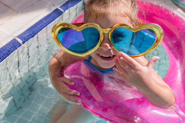 可爱的女孩在游泳池戴着心形太阳镜。图片下载
