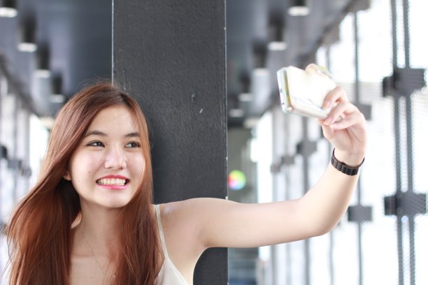 泰国成年美丽的女孩使用她的智能手机自拍。图片下载