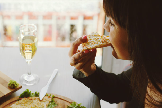 女孩咬着奶酪馅的派。图片下载