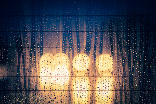 雨点落在汽车挡风玻璃上，路面灯光变得模糊图片下载