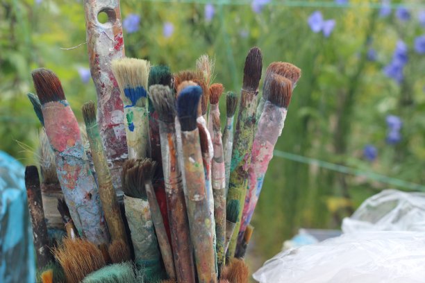 不同颜色的笔刷在桶上的绿色背景图片下载