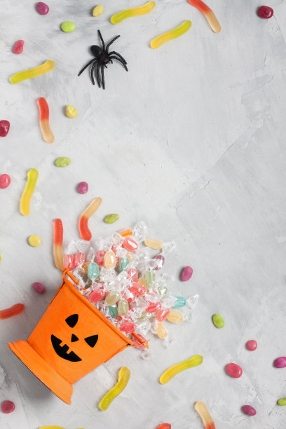 灰色混凝土背景上装着糖果和枣子的万圣节桶图片下载