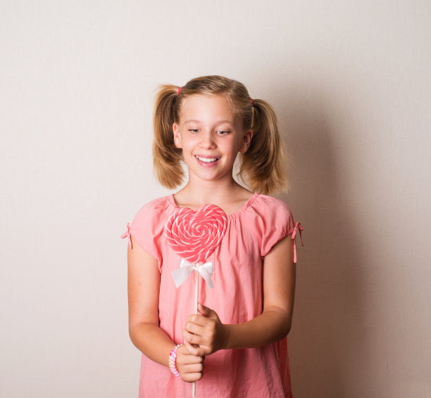 漂亮的小女孩拿着一个大的心形棒棒糖图片下载