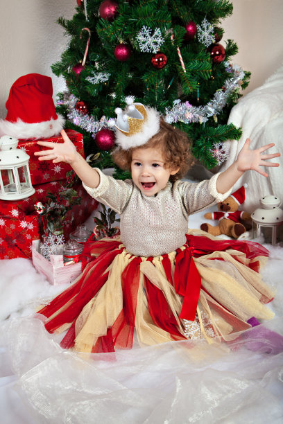 卷毛女孩站在圣诞树前图片下载