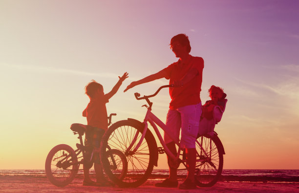 父亲和两个孩子骑自行车的剪影图片下载