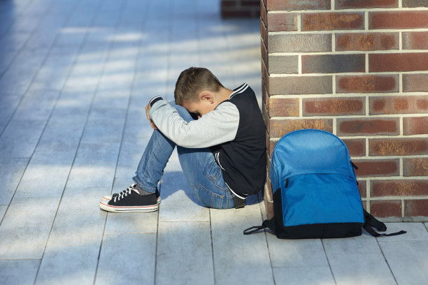 在学校走廊里哭泣的男学生素材图片