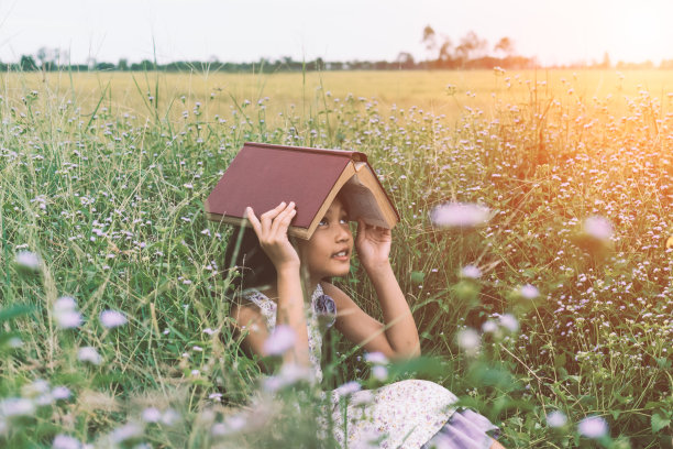 快乐的女孩在公园里看书图片下载