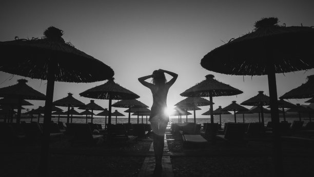 性感的女人走在日落的海滩上图片下载