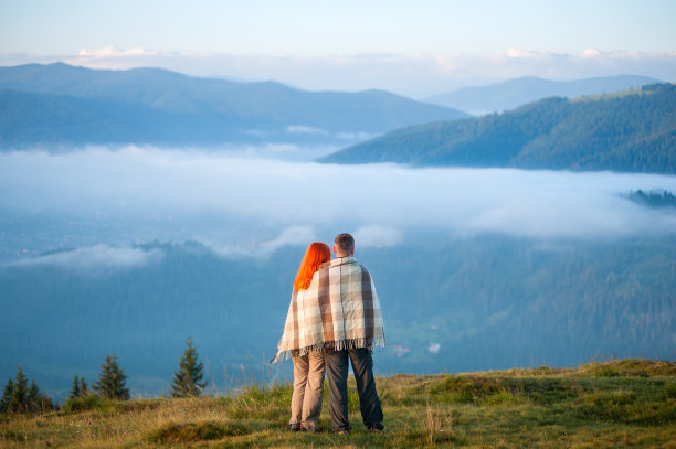 一对夫妇站在山上欣赏清晨的薄雾图片下载